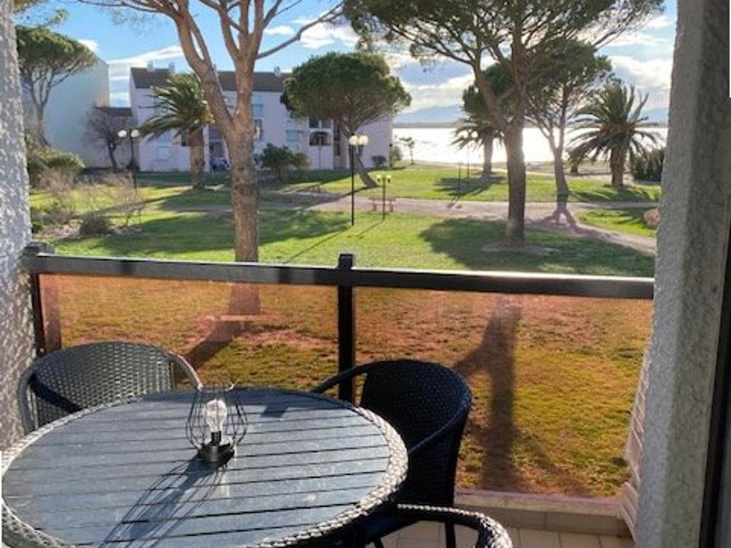 une table et des chaises sur un balcon avec vue sur l'océan dans l'établissement Studio Cabine à Le Barcarès, 4 couchages, terrasse, parking, piscine et activités sportives - FR-1-195-23, au Barcarès