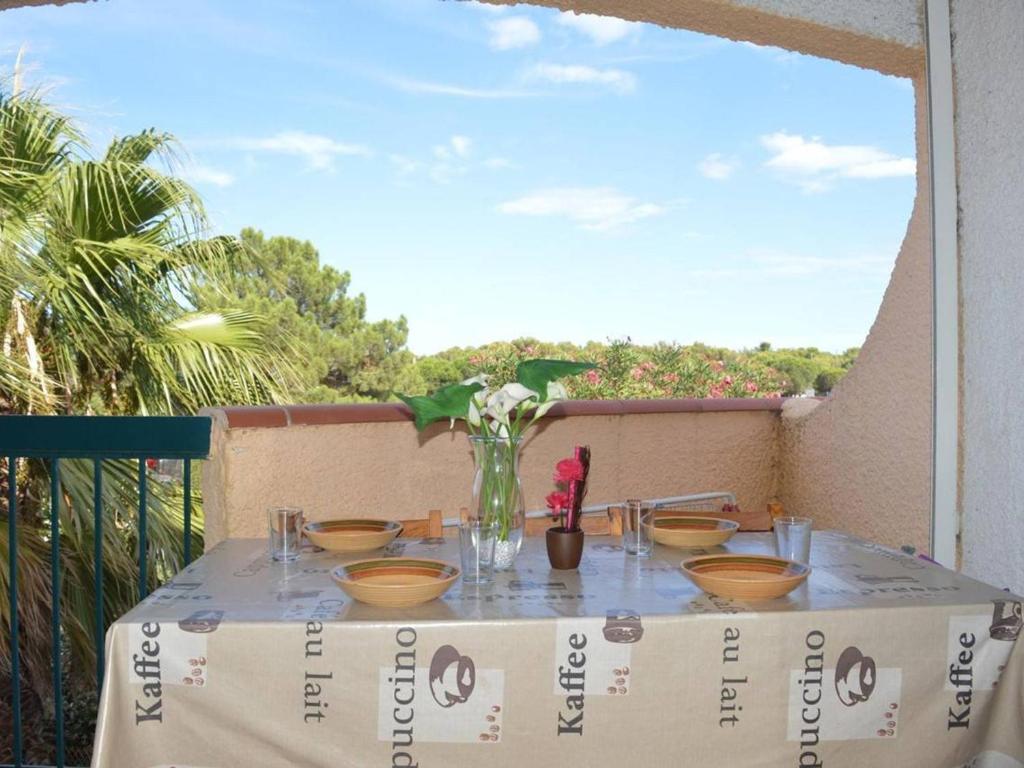 une table avec des bols et un vase avec des fleurs dans l'établissement Bel Appart 2P 4 Couchages proche Plage - Terrasse, Parking, Animaux Ok - FR-1-225-60, à Argelès-sur-Mer
