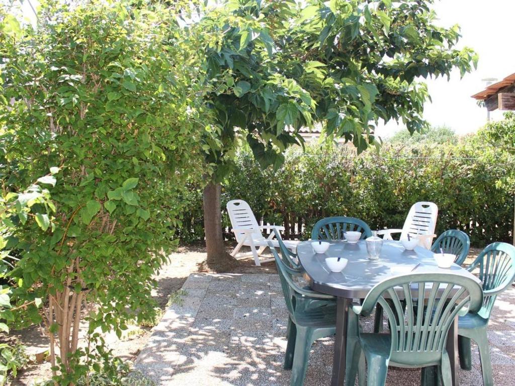 une table bleue et des chaises assises sous un arbre dans l'établissement Maison Gruissan, 3 pièces, 6 personnes - FR-1-229-53, à Gruissan