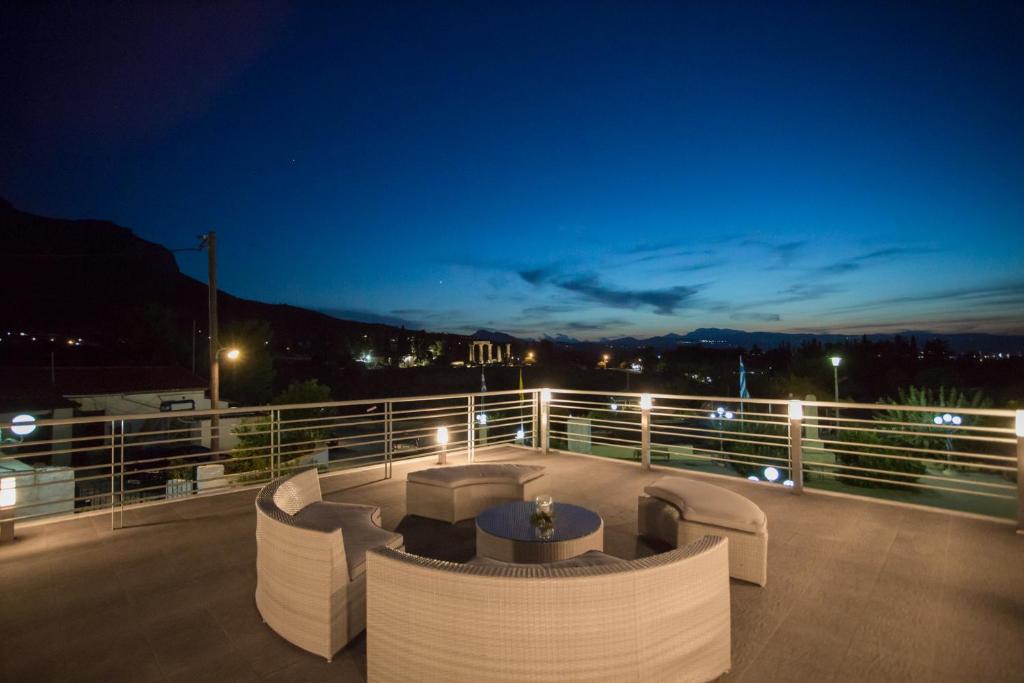 una terraza con sofás y una mesa en el balcón por la noche en Apollonio Upper View Suites, en Korinthos