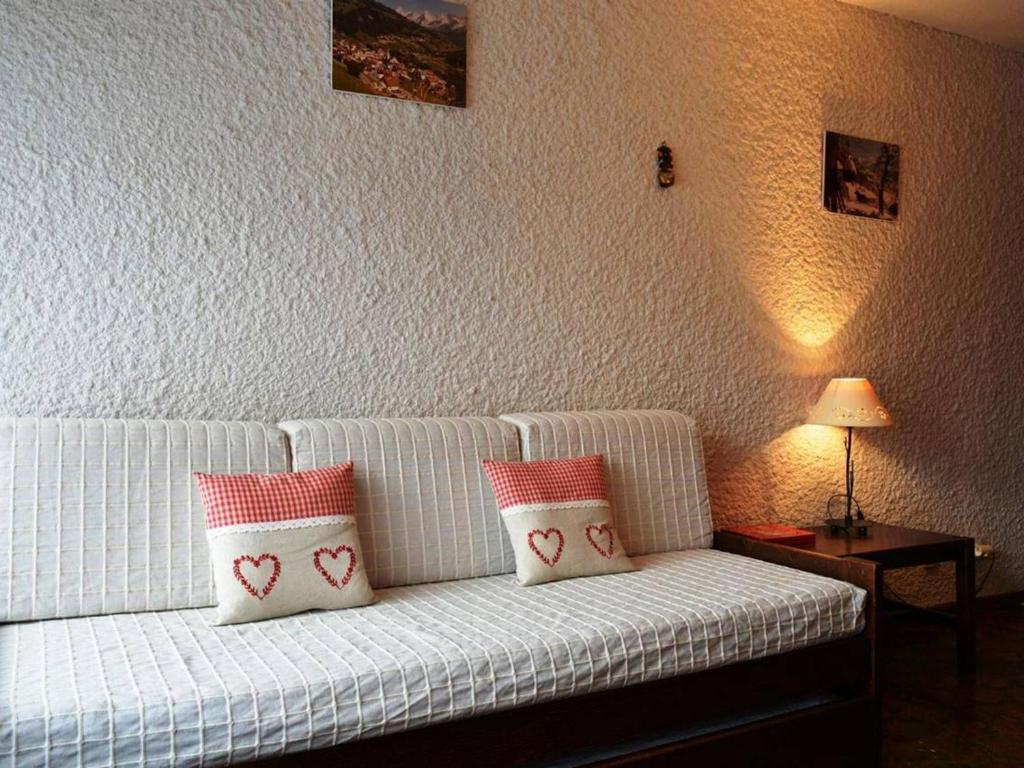 a white couch with red and white pillows on it at Appartement Le Grand-Bornand, 1 pièce, 4 personnes - FR-1-241-80 in Le Grand-Bornand