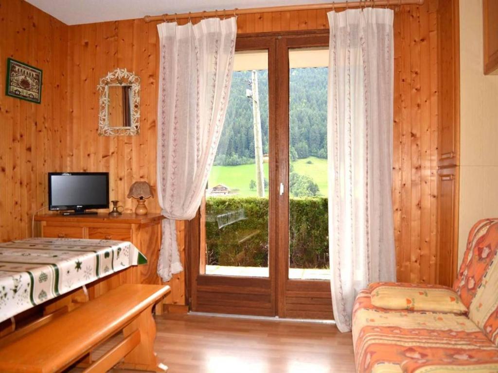 a bedroom with a sliding glass door and a television at Appartement Le Grand-Bornand, 1 pièce, 4 personnes - FR-1-241-95 in Le Grand-Bornand