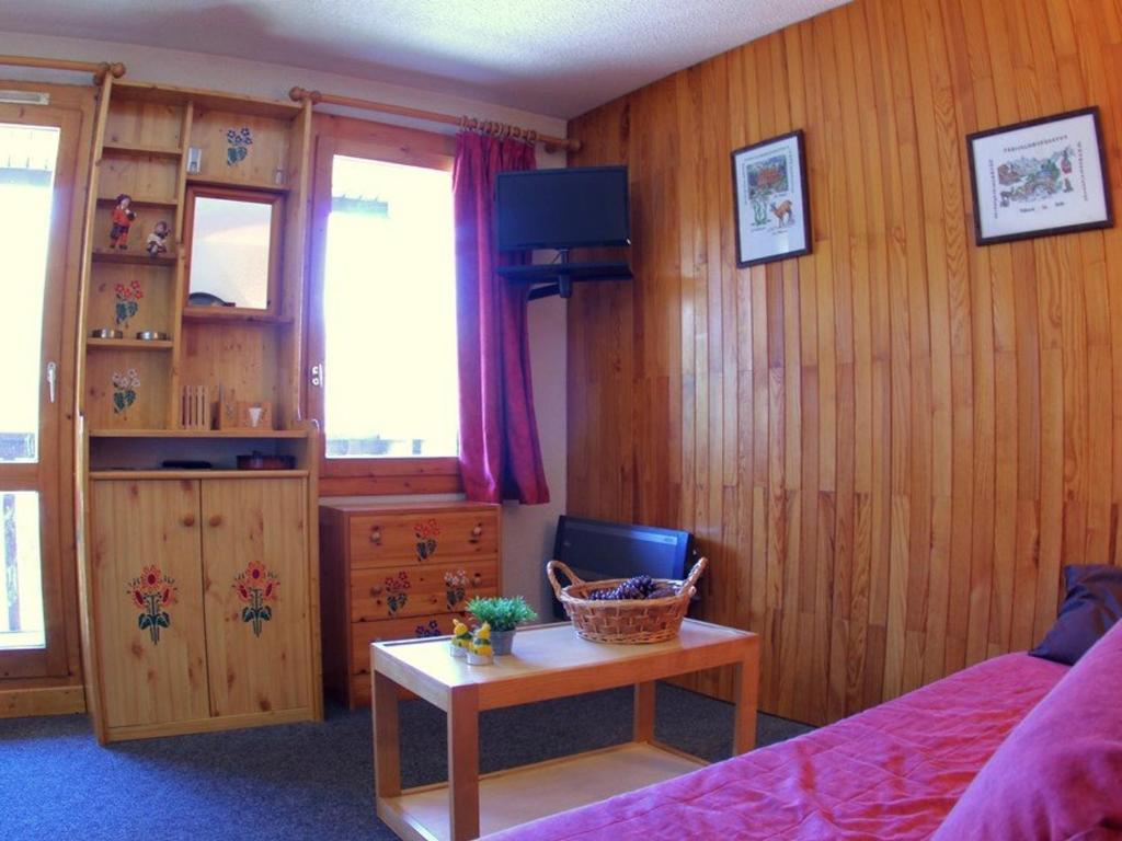 ヴァルモレルにあるAppartement Valmorel, 2 pièces, 6 personnes - FR-1-291-721の木製の壁のベッドルーム1室、ベッド1台、テーブルが備わります。