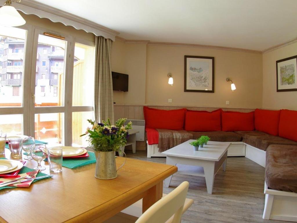 ein Wohnzimmer mit einem roten Sofa und einem Tisch in der Unterkunft Appartement cosy 3 pièces - 7 pers, skis aux pieds, 2 salles de bain, parking disponible - FR-1-291-747 in Valmorel