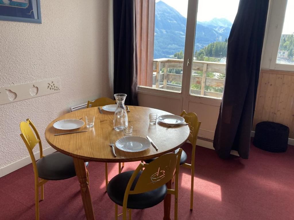 ein Esstisch mit Stühlen und ein großes Fenster in der Unterkunft Maxi studio lumineux pour 4 pers. à Orcières Merlette, proche pistes et commerces, loggia sud - FR-1-262-128 in Forest des Baniols