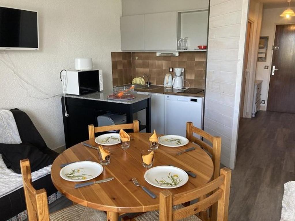 einen Holztisch mit vier Stühlen und eine Küche in der Unterkunft Maxi studio lumineux 6 pers, accès direct aux pistes, sud/ouest, proche commerces et sports - FR-1-262-138 in Forest des Baniols