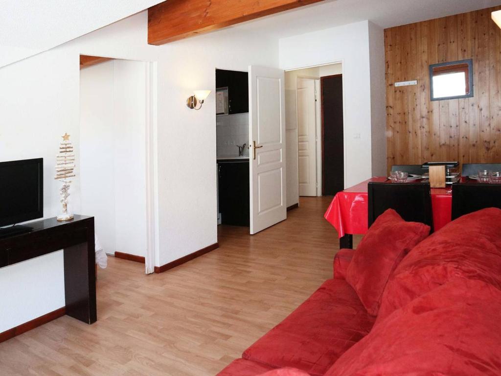 un salon avec un canapé rouge et une cuisine dans l'établissement Appartement de standing avec piscine, sauna, hamman et wifi aux Orres 1800 - FR-1-322-44, aux Orres