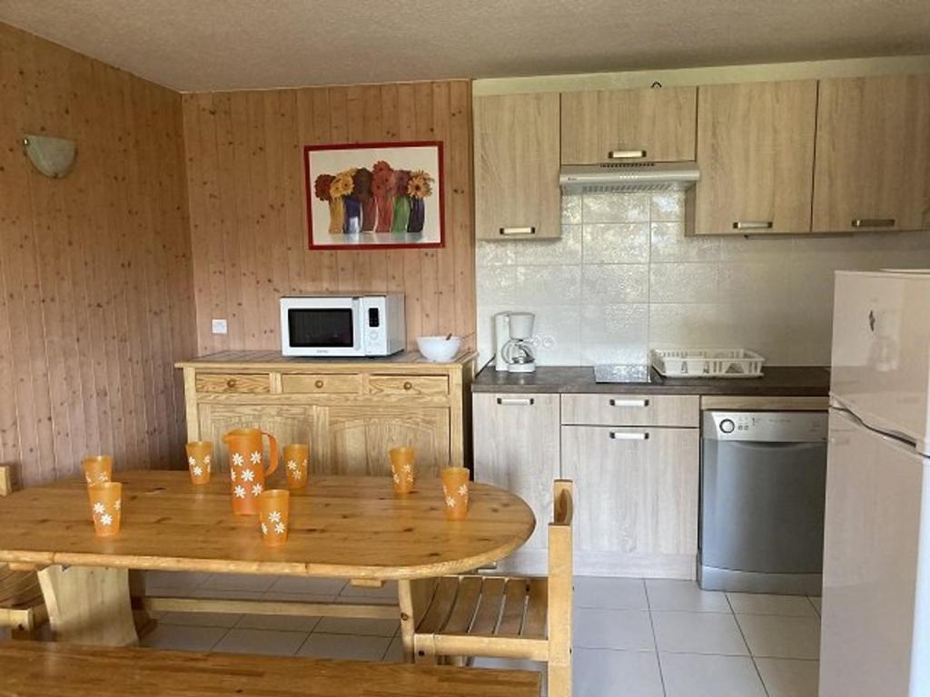 cocina con mesa de madera y nevera en Appartement Orcières Merlette, 2 pièces, 8 personnes - FR-1-262-87, en Forest des Baniols