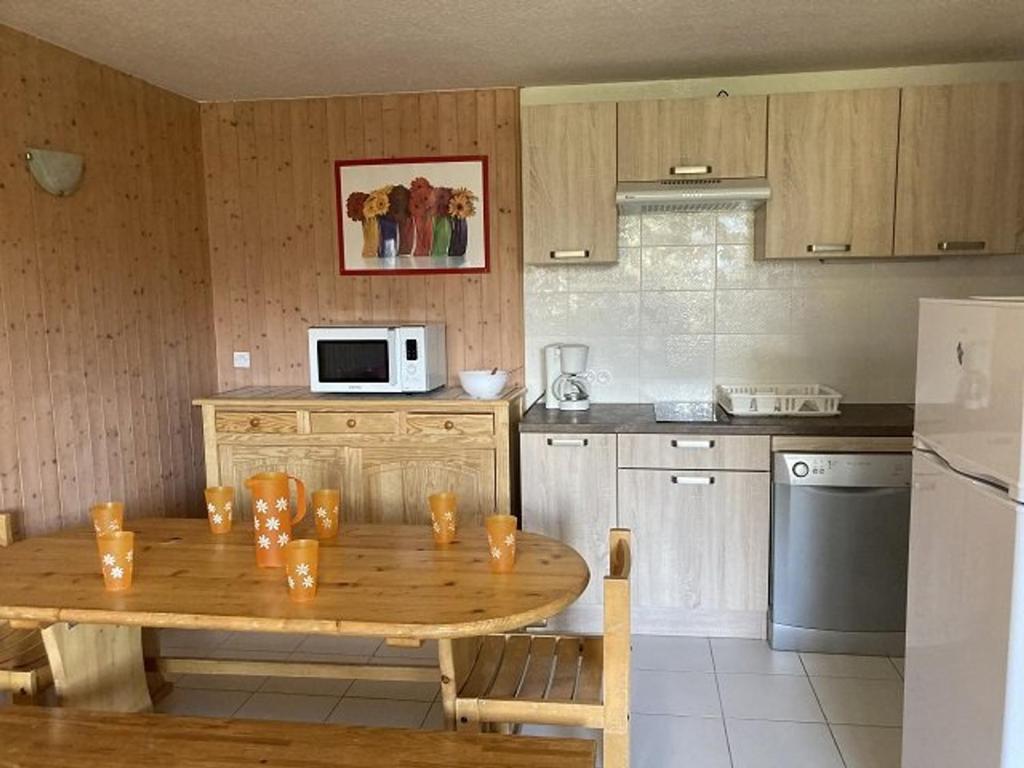 Appartement 2 pièces cabine 8 pers, proche pistes et commerces, Orcières - FR-1-262-87 في Forest des Baniols: مطبخ مع طاولة خشبية وثلاجة