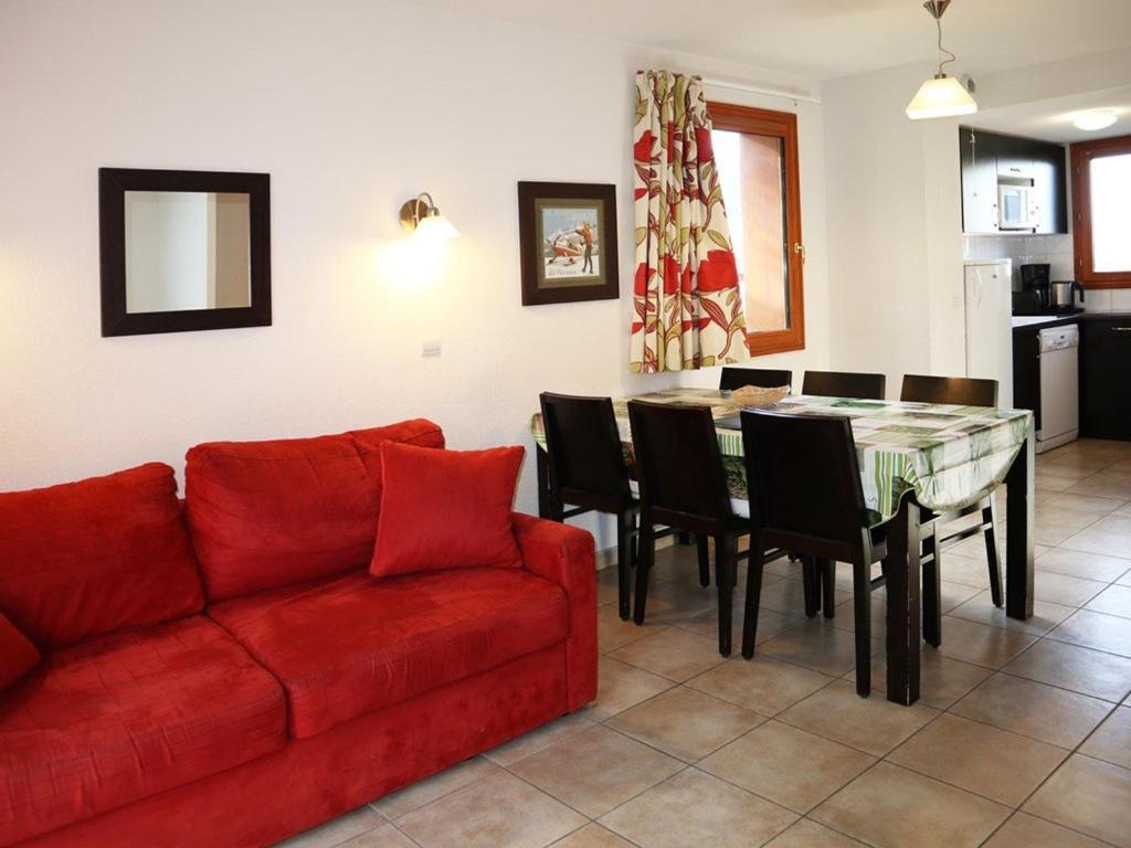 a living room with a red couch and a table at Chalet confortable avec piscine & sauna, aux pieds des pistes des Orres 1800, grand duplex pour 6 pers. - FR-1-322-57 in Les Orres