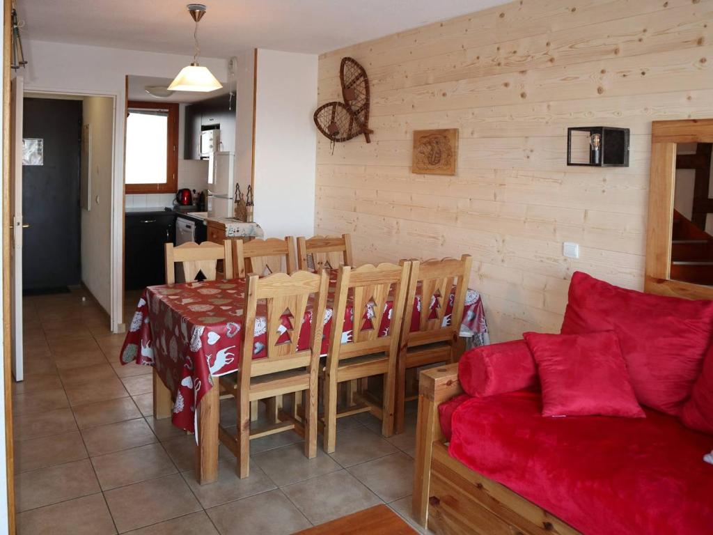 a living room with a table and a red couch at Chalet Les Orres, 3 pièces, 6 personnes - FR-1-322-63 in Les Orres