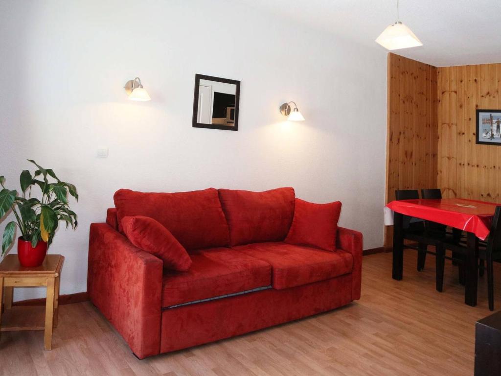 a red couch in a living room with a table at Appartement Les Orres, 2 pièces, 4 personnes - FR-1-322-75 in Les Orres