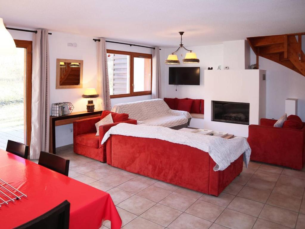 uma sala de estar com uma cama vermelha e uma lareira em Chalet Les Orres, 5 pièces, 10 personnes - FR-1-322-118 em Les Orres