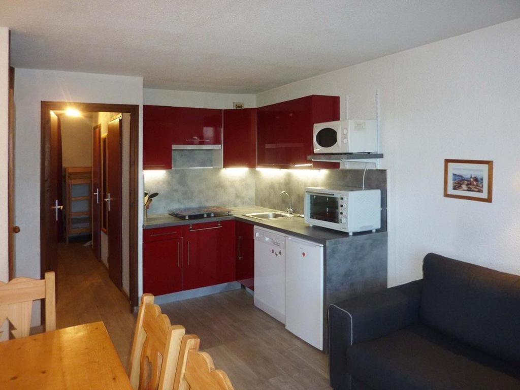 レ・ゾルにあるAppartement Les Orres, 1 pièce, 6 personnes - FR-1-322-59の赤いキャビネットとソファ付きのキッチンが備わります。