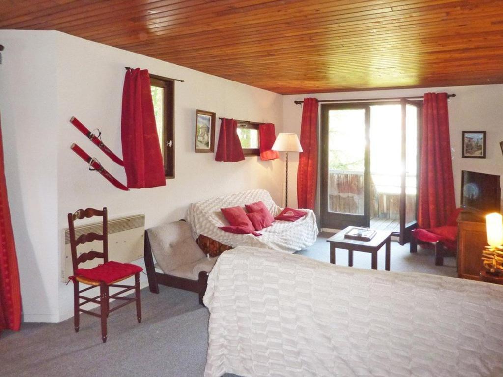 a bedroom with a bed and a couch and red curtains at Appartement Les Orres, 2 pièces, 6 personnes - FR-1-322-276 in Les Orres