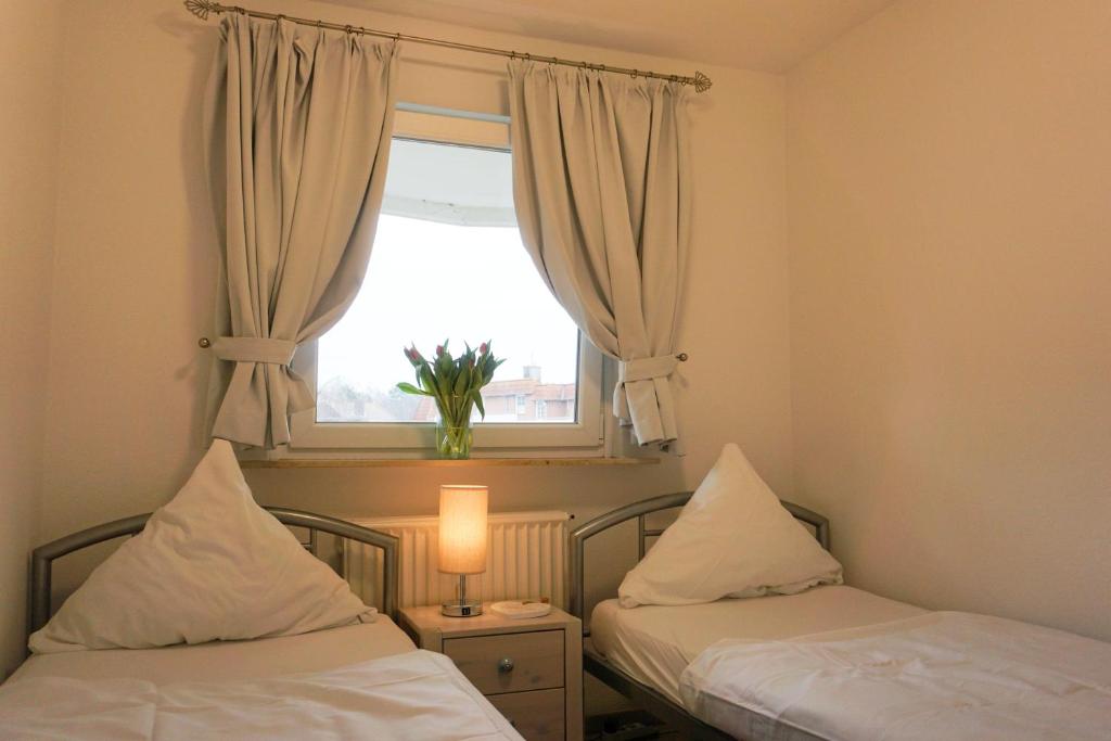 two beds in a small room with a window at Grosszuegige-Ferienwohnung-im-OT-Bad-Strandnaehe in Sankt Peter-Ording