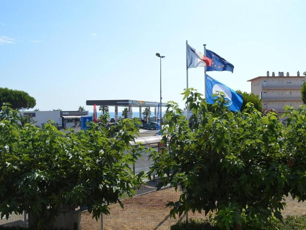 duas bandeiras a voar em frente a um edifício com árvores em Appartement Saint-Cyprien, 2 pièces, 4 personnes - FR-1-225D-440 em Saint-Cyprien-Plage