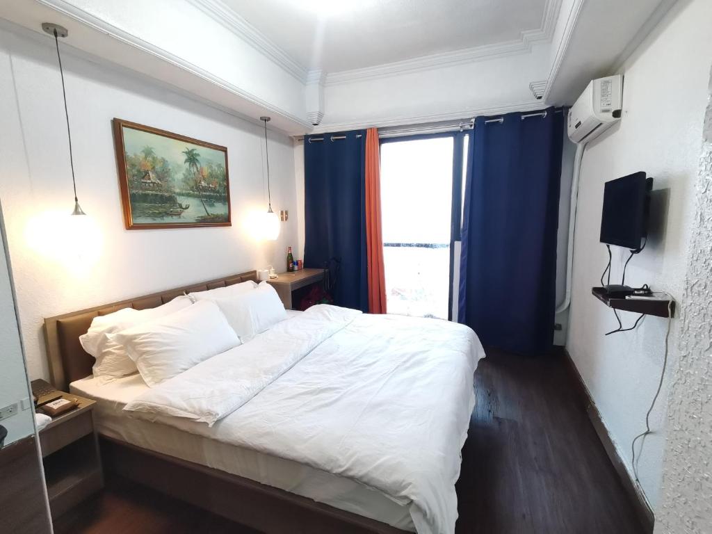 a bedroom with a large white bed with blue curtains at Accommodation Service in Manila
