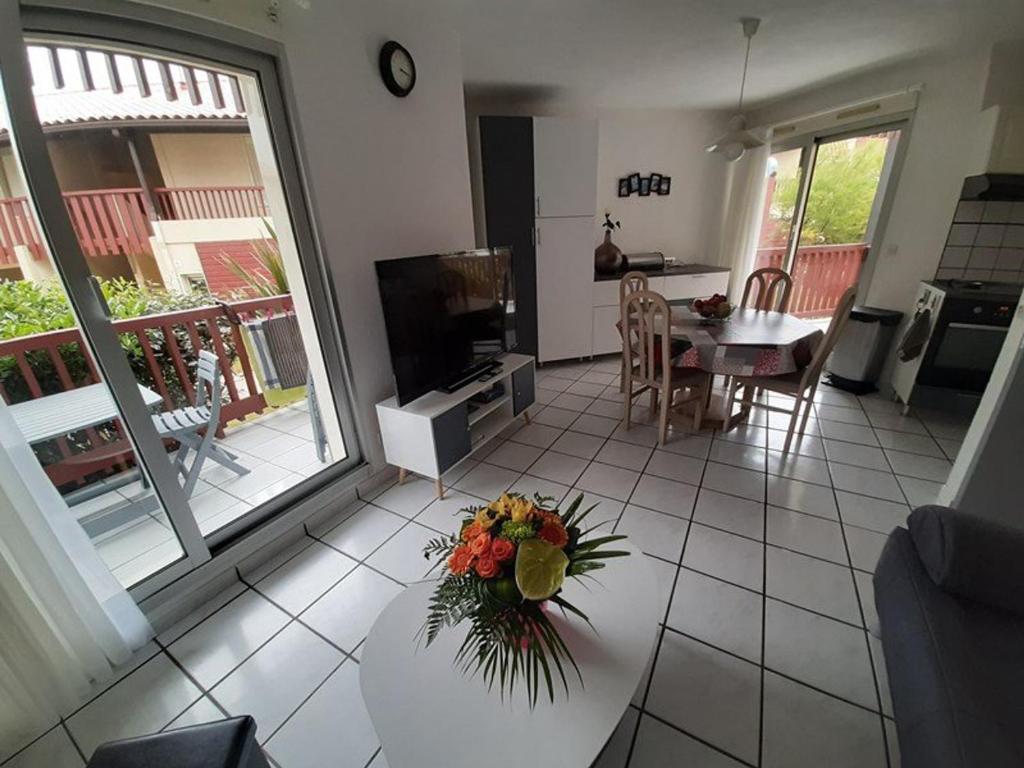 een woonkamer met een tafel met een vaas met bloemen erop bij Appartement T2 cabine avec terrasse et piscine à Vieux-Boucau, idéal pour les vacances ! - FR-1-379-18 in Vieux-Boucau-les-Bains