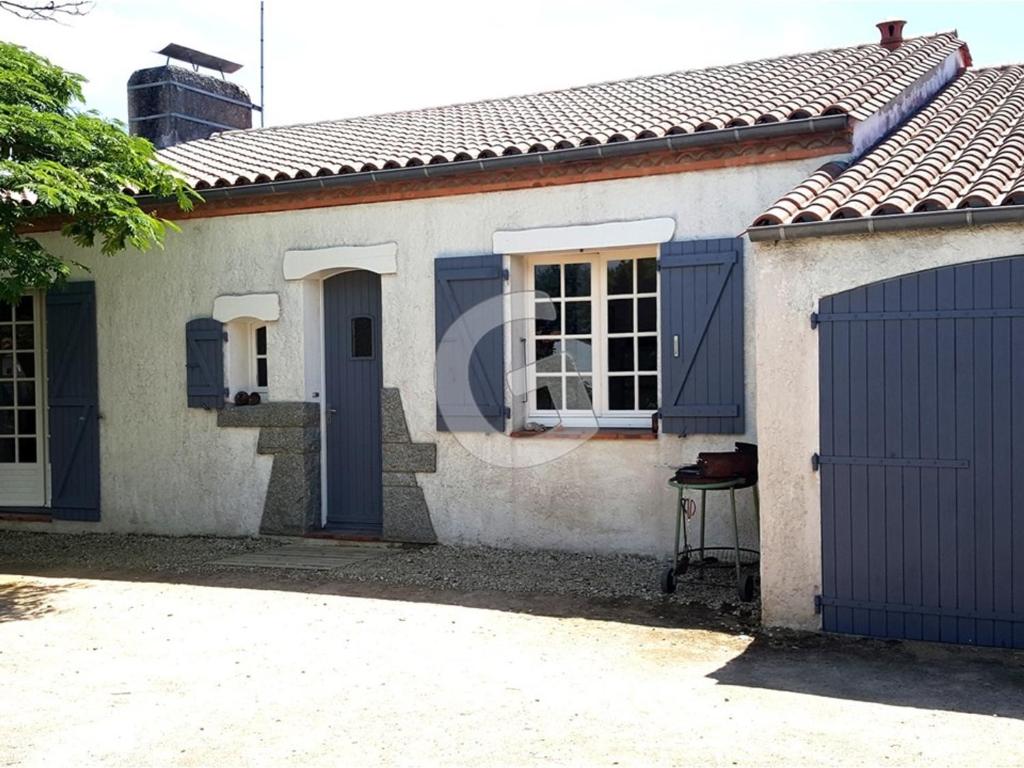 une maison blanche avec des portes bleues et un portail dans l'établissement Maison familiale proche plage avec jardin et parking à Saint-Vincent-sur-Jard - FR-1-357-32, à Saint-Vincent-sur-Jard
