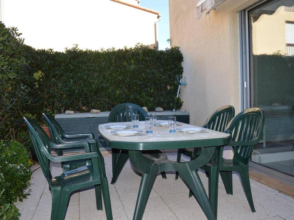 une table verte avec quatre chaises sur la terrasse dans l'établissement Appartement T2 en Rez-de-Chaussée avec Terrasse et Parking à Saint-Cyprien - FR-1-225D-472, à Saint Cyprien Plage