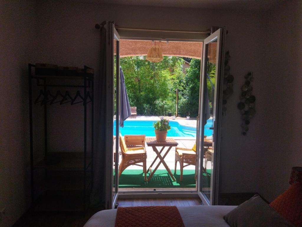 a sliding glass door leading to a patio with a pool at Le Mas Victoria - Chambres d'hôtes avec table d'hôtes-Parking privé ferme in Carcassonne