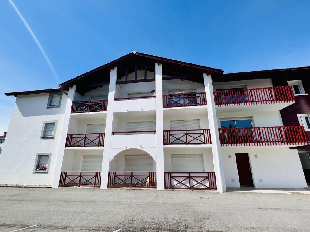 een wit appartementencomplex met rode balkons erop bij Studio Cambo-les-Bains, 1 pièce, 4 personnes - FR-1-495-64 in Cambo-les-Bains