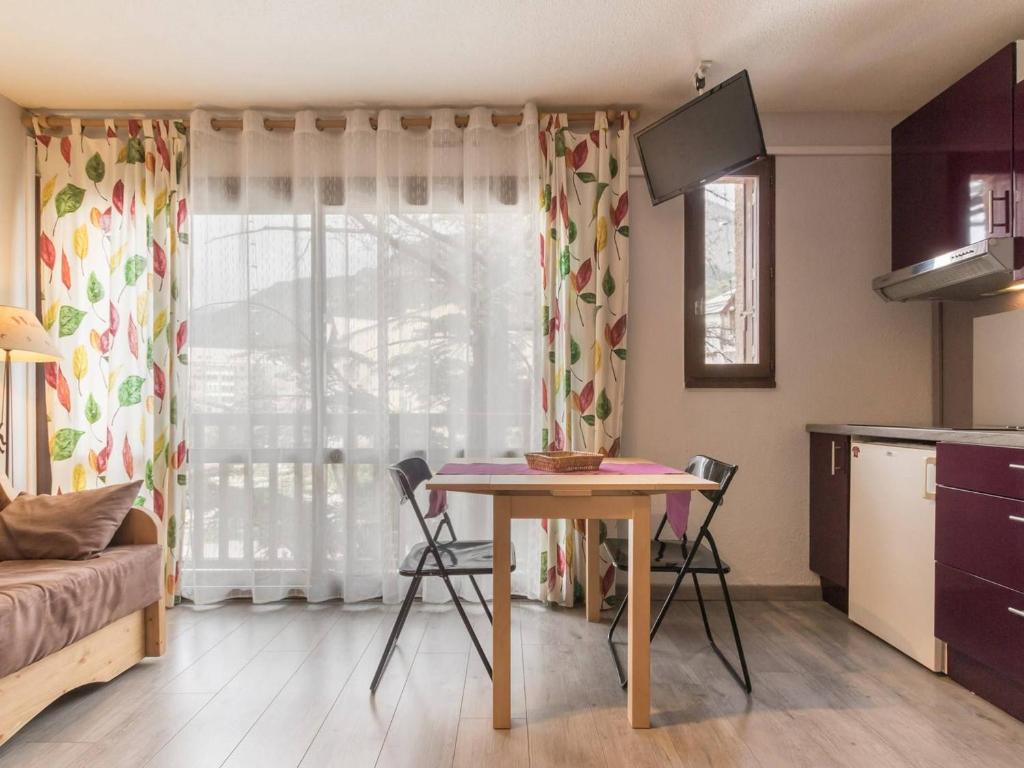 eine Küche mit Tisch und Stühlen in einem Zimmer in der Unterkunft Studio cosy avec coin nuit, proche télécabine et centre, parking - FR-1-330C-21 in Briançon