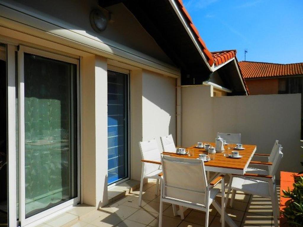 una mesa de madera y sillas en un patio en Appartement Vieux-Boucau-les-Bains, 3 pièces, 6 personnes - FR-1-379-28, en Vieux-Boucau-les-Bains