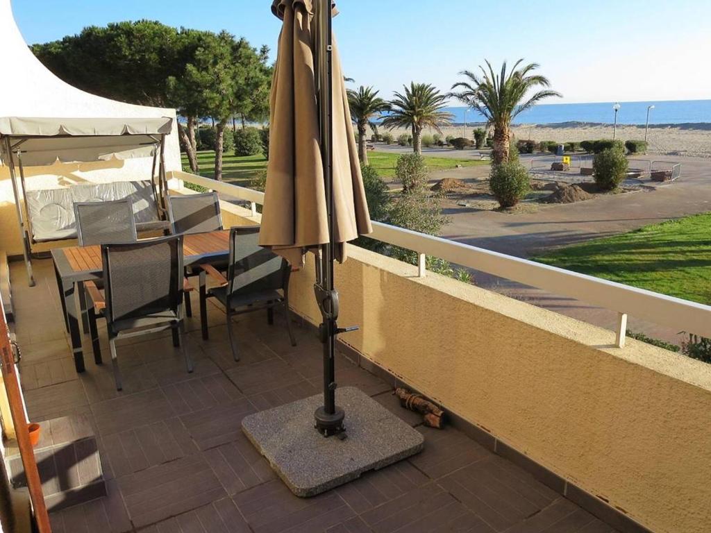 un parasol installé sur un balcon avec une table et des chaises dans l'établissement T3 climatisé avec wifi, terrasse, parking - Argelès-sur-Mer - FR-1-388-82, à Argelès-sur-Mer