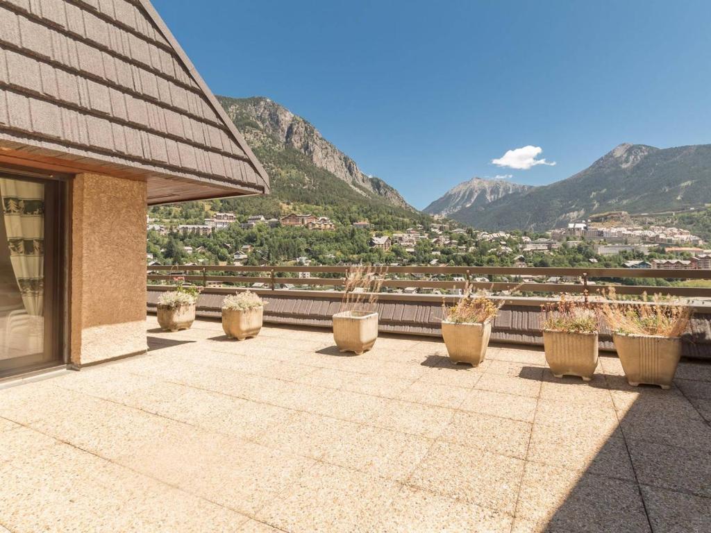 une rangée de plantes en pot sur un balcon avec des montagnes dans l'établissement Appartement Briançon, 3 pièces, 6 personnes - FR-1-330C-30, à Briançon