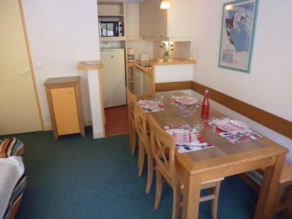 Il comprend une cuisine avec une table et des chaises en bois ainsi qu'une cuisine équipée d'un réfrigérateur. dans l'établissement Appartement 6 pers, pied des pistes, balcon, parking couvert, animaux OK, Grand Tourmalet - FR-1-404-56, à La Mongie