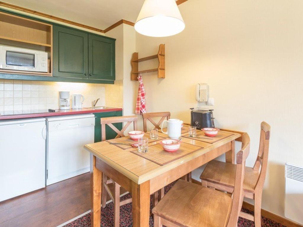 une cuisine avec une table en bois et quelques chaises dans l'établissement Charmant 2 pièces au cœur de La Salle-les-Alpes, proche télécabines et commerces, 4 couchages - FR-1-330F-45, à Serre Chevalier