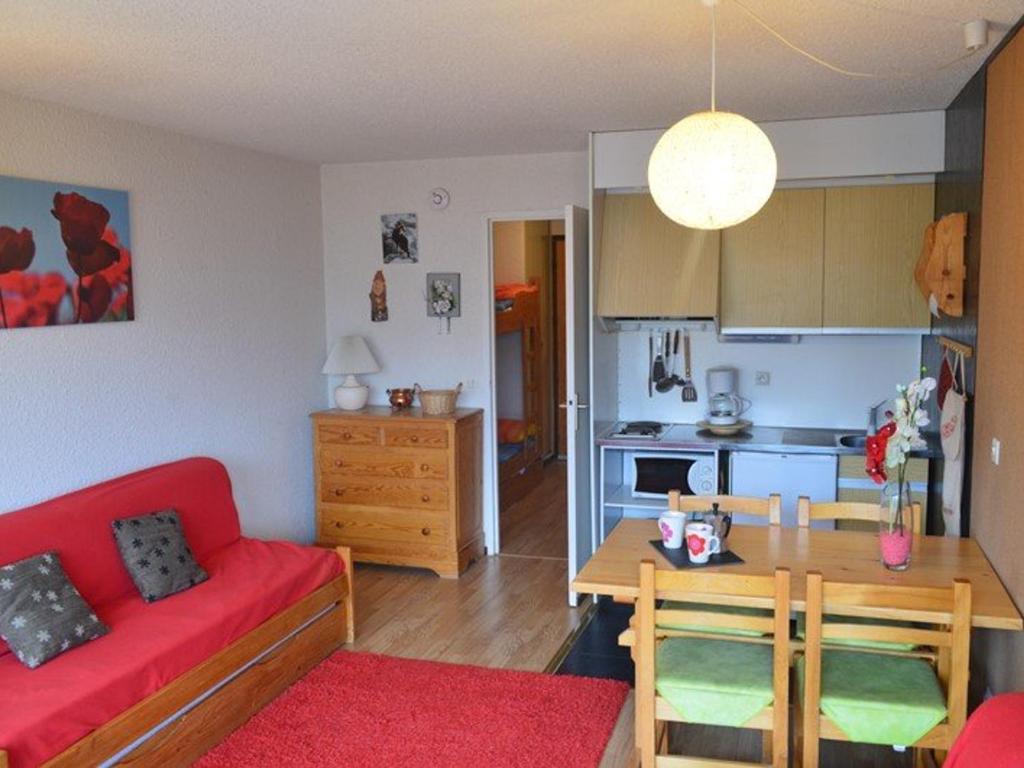 ein Wohnzimmer mit einem roten Sofa und einer Küche in der Unterkunft Studio Montgenèvre, 1 pièce, 4 personnes - FR-1-266-102 in Montgenèvre