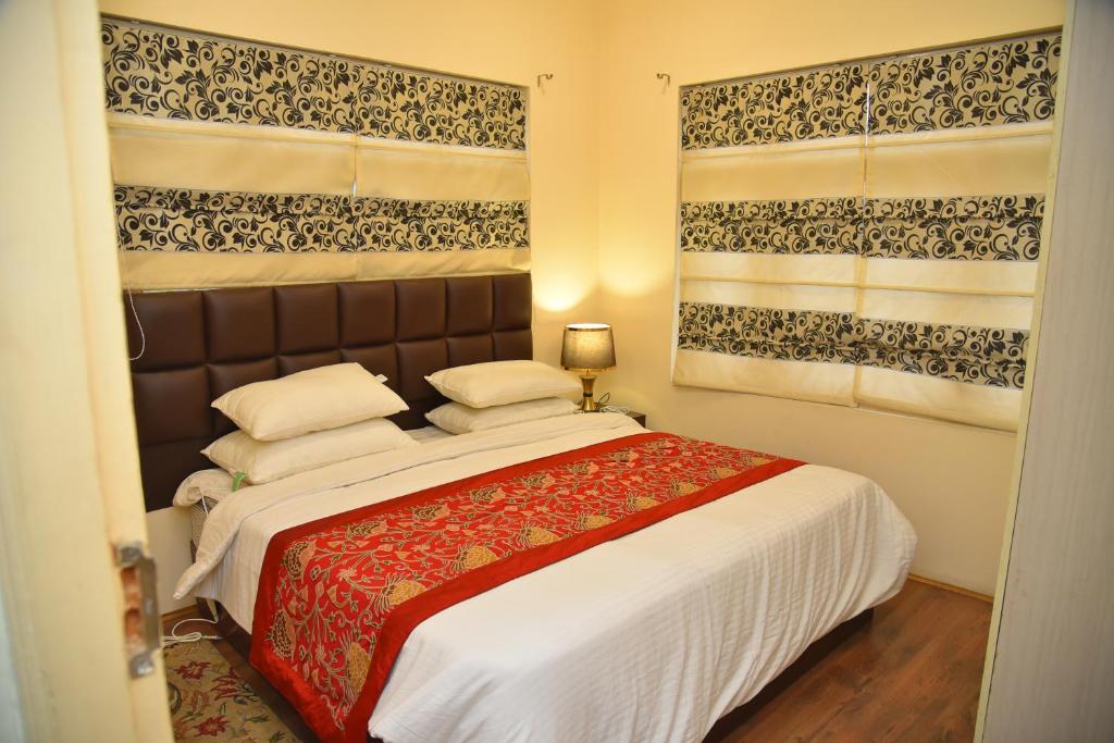 um quarto com uma cama grande e 2 janelas em Himalayan Sun Cottage em Srinagar