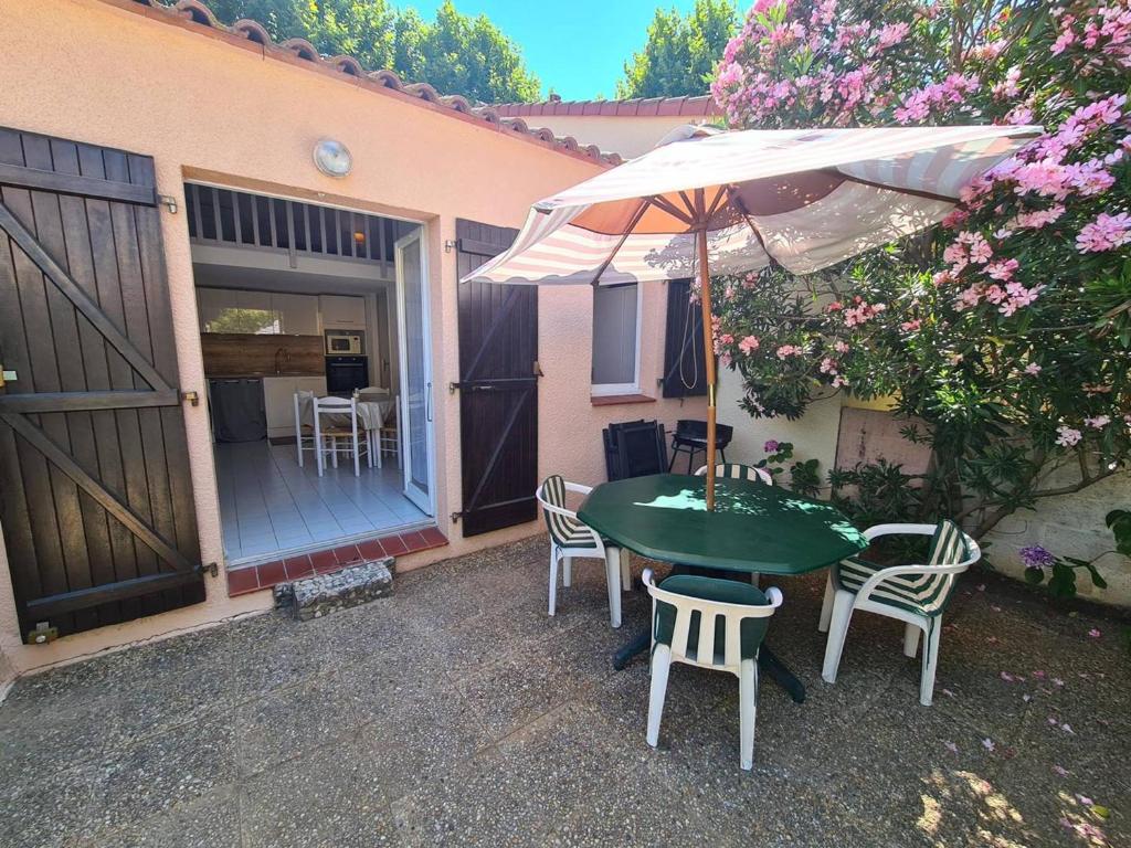 une table et des chaises avec un parasol sur une terrasse dans l'établissement Pavillon Studio Mezzanine 4 Pers avec Piscine, Terrasse et Parking à Argelès-sur-Mer - FR-1-388-91, à Argelès-sur-Mer