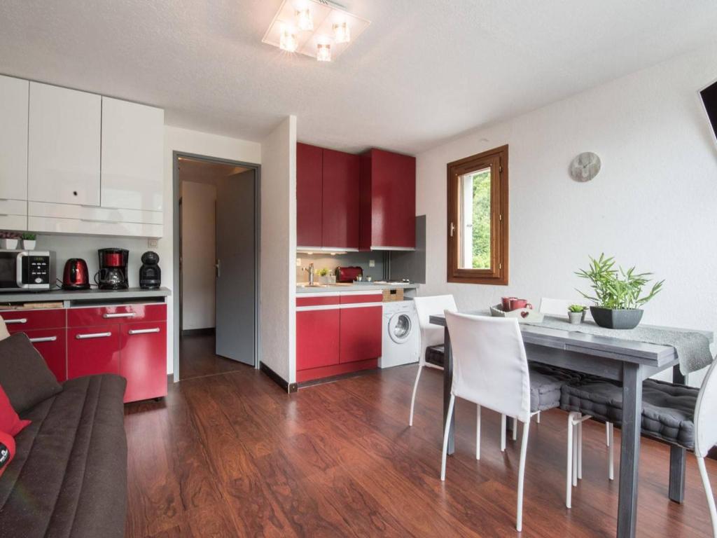 a kitchen and living room with red cabinets and a table at Appartement Saint-Lary-Soulan, 2 pièces, 4 personnes - FR-1-296-239 in Saint-Lary-Soulan