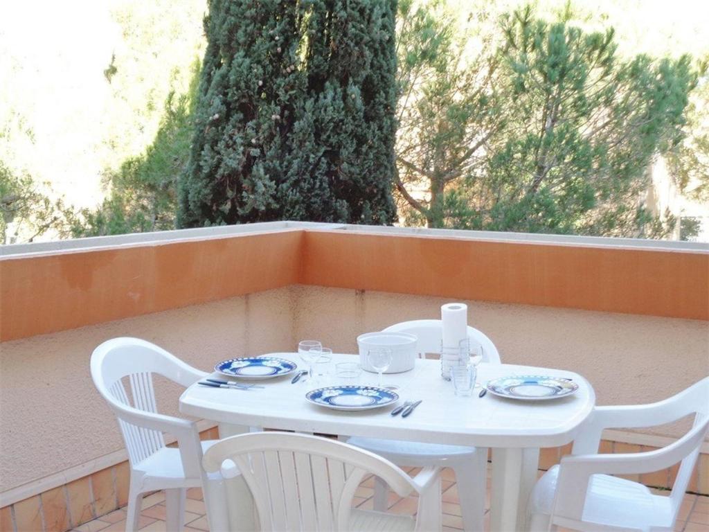 une table et des chaises blanches assises sur un balcon dans l'établissement Appartement T2 à 200m de la plage avec terrasse, parking, 5 couchages - Argelès-sur-Mer - FR-1-388-126, à Argelès-sur-Mer