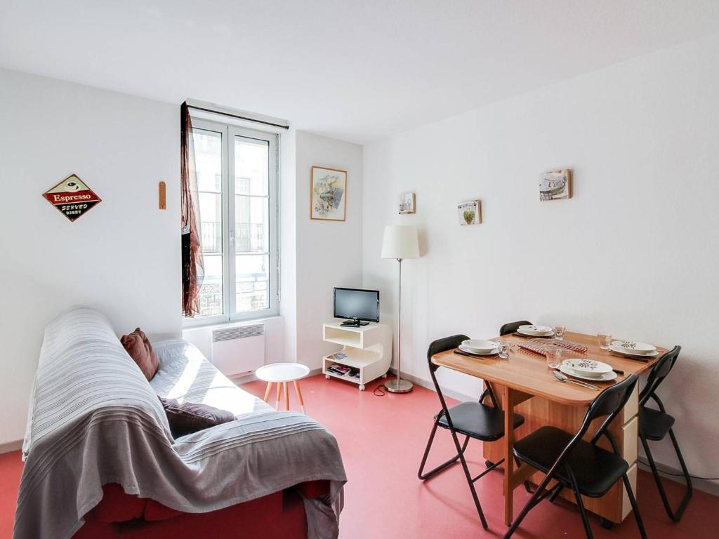 une personne assise sur un canapé dans une pièce avec une table dans l'établissement Appartement T2 avec coin nuit, face télécabine, 4 pers, plein centre, Cauterets - FR-1-401-7, à Cauterets