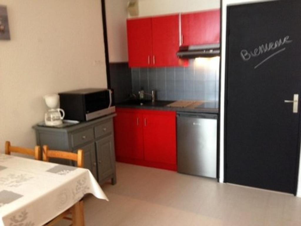 een keuken met rode kasten en een zwarte koelkast bij Studio La Mongie, 2 pièces, 6 personnes - FR-1-404-111 in La Mongie