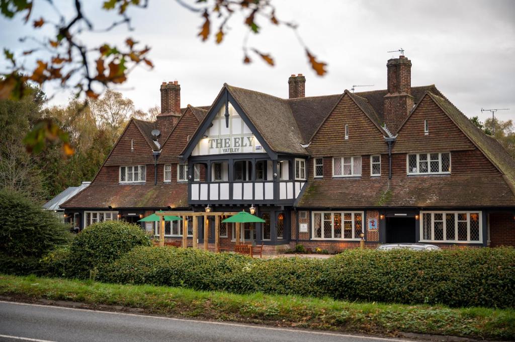 ein großes braun-weißes Gebäude am Straßenrand in der Unterkunft Ely Hotel by Chef & Brewer Collection in Camberley