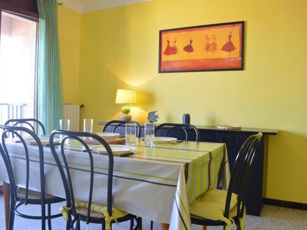 d'une salle à manger avec une table, des chaises et un mur jaune. dans l'établissement Grand T2 lumineux avec parking à 300m de la plage de Banyuls-sur-Mer - FR-1-225C-534, à Banyuls-sur-Mer