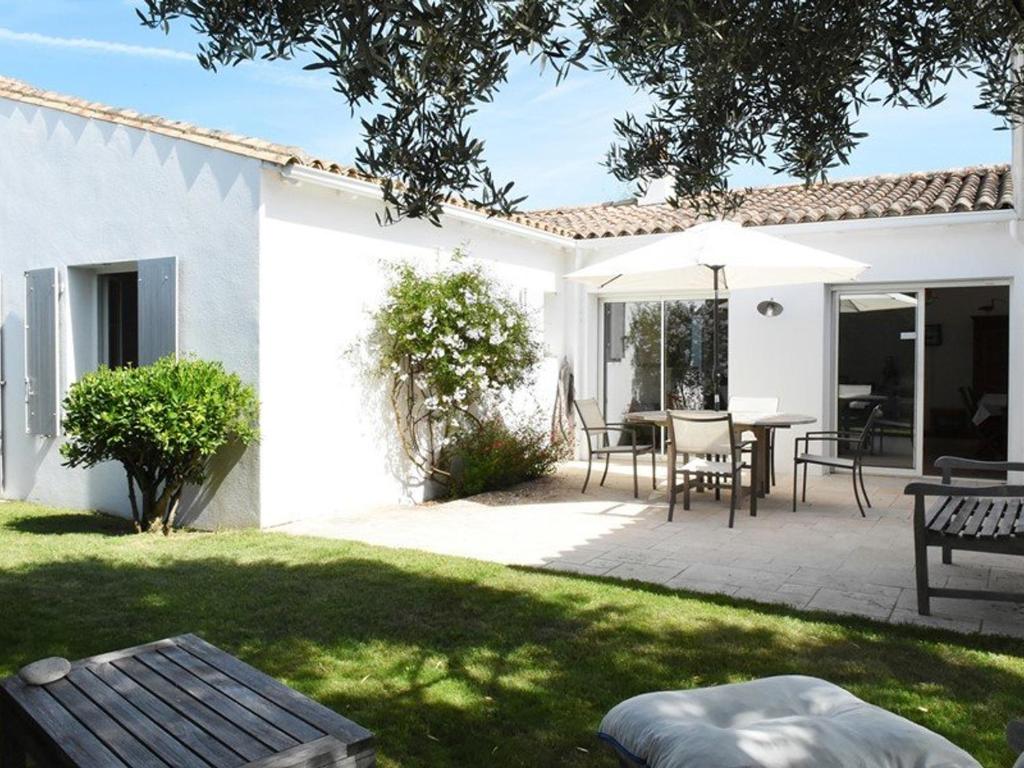 a backyard with a table and chairs and an umbrella at Maison Les Portes-en-Ré, 4 pièces, 6 personnes - FR-1-434-10 in Les Portes