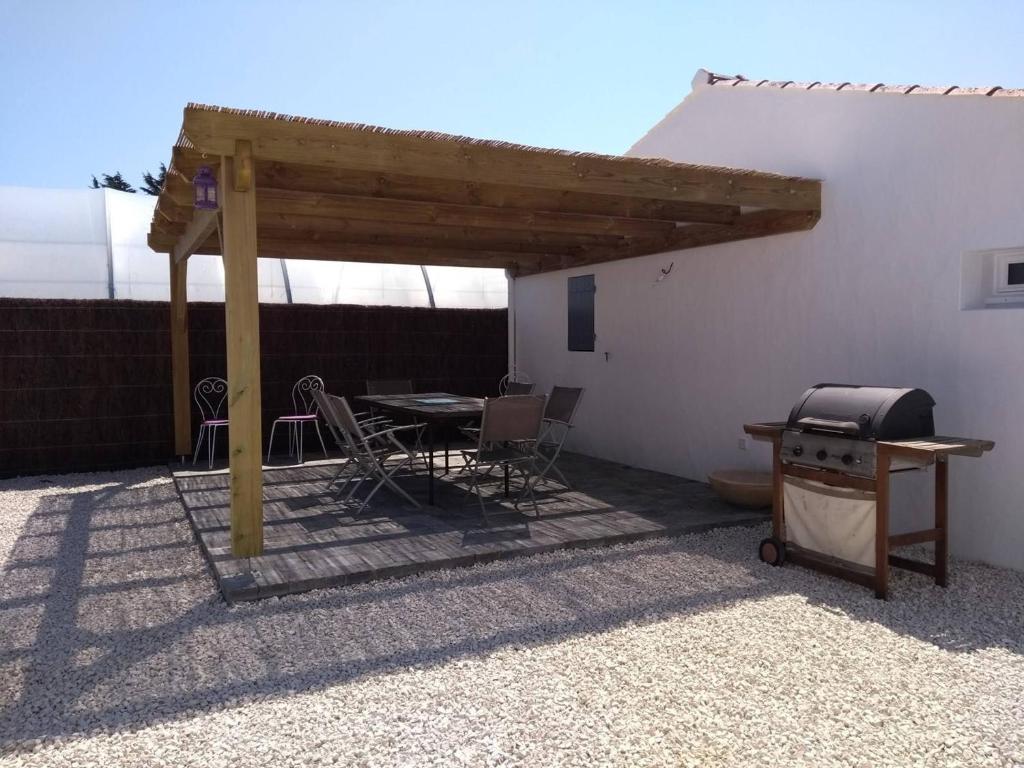 a wooden pergola with a table and a grill at Maison Noirmoutier-en-l&#39;Île, 4 pièces, 6 personnes - FR-1-224B-646 in Noirmoutier-en-l&#39;lle