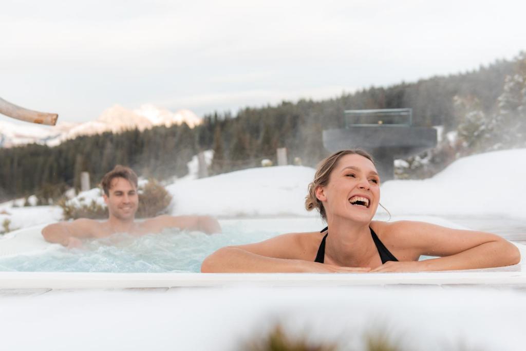 un hombre y una mujer en un jacuzzi en Dolomites Living Hotel Tirler, en Alpe di Siusi