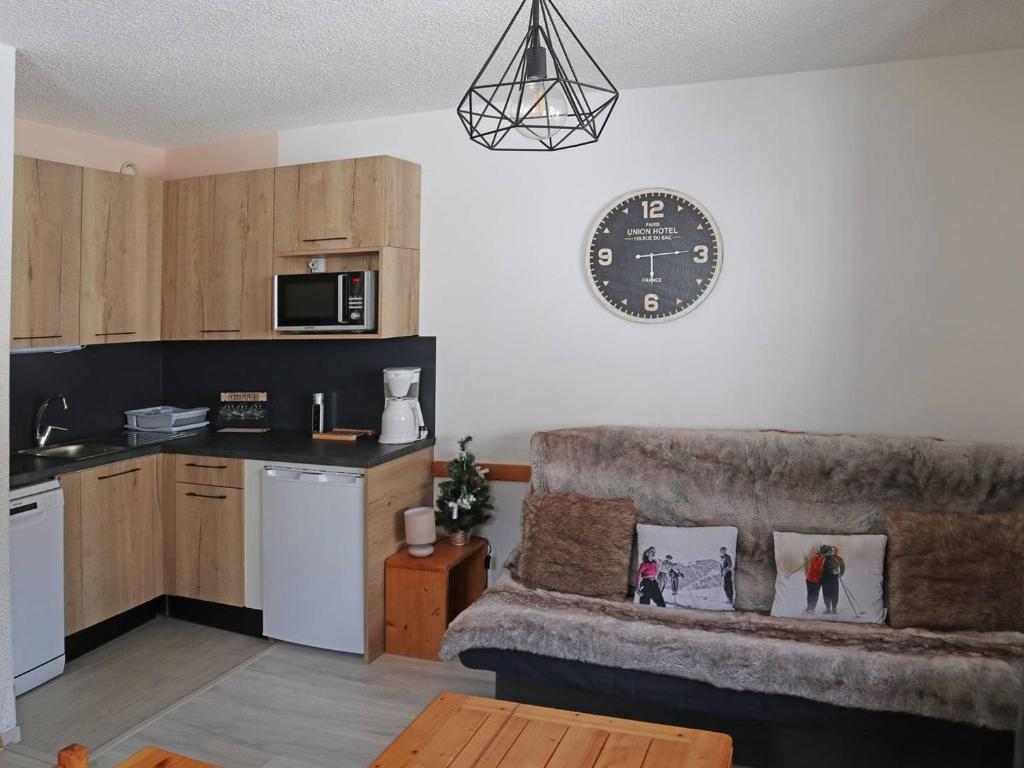 a living room with a couch and a clock on the wall at Studio Les Orres, 1 pièce, 4 personnes - FR-1-322-323 in Les Orres