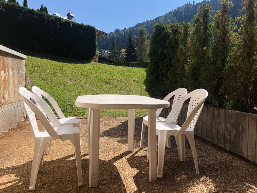 une table blanche et quatre chaises blanches assises autour de celle-ci dans l'établissement Charmant studio avec terrasse et WIFI à La Clusaz - FR-1-459-64, à La Clusaz