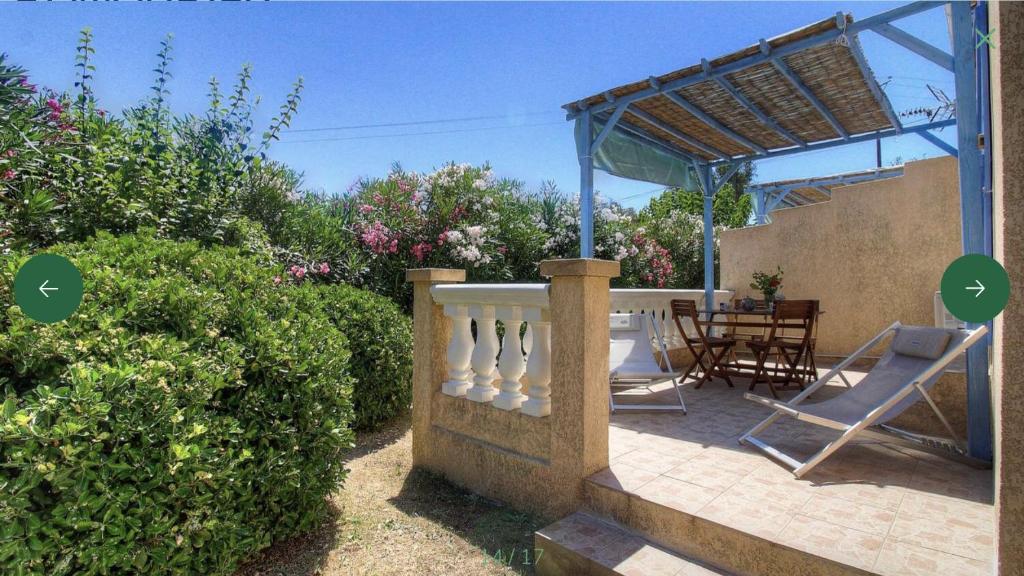 a patio with a wooden table and chairs and bushes at L'AMANDIER -LE FIGUIER-LES LAURIERS ROSES in Ajaccio