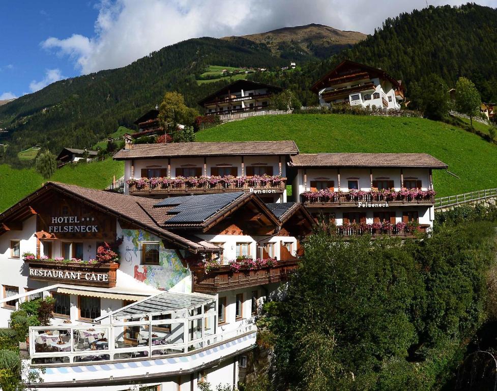 a hotel on a hill with people on a balcony at Pension Felseneck in San Leonardo in Passiria