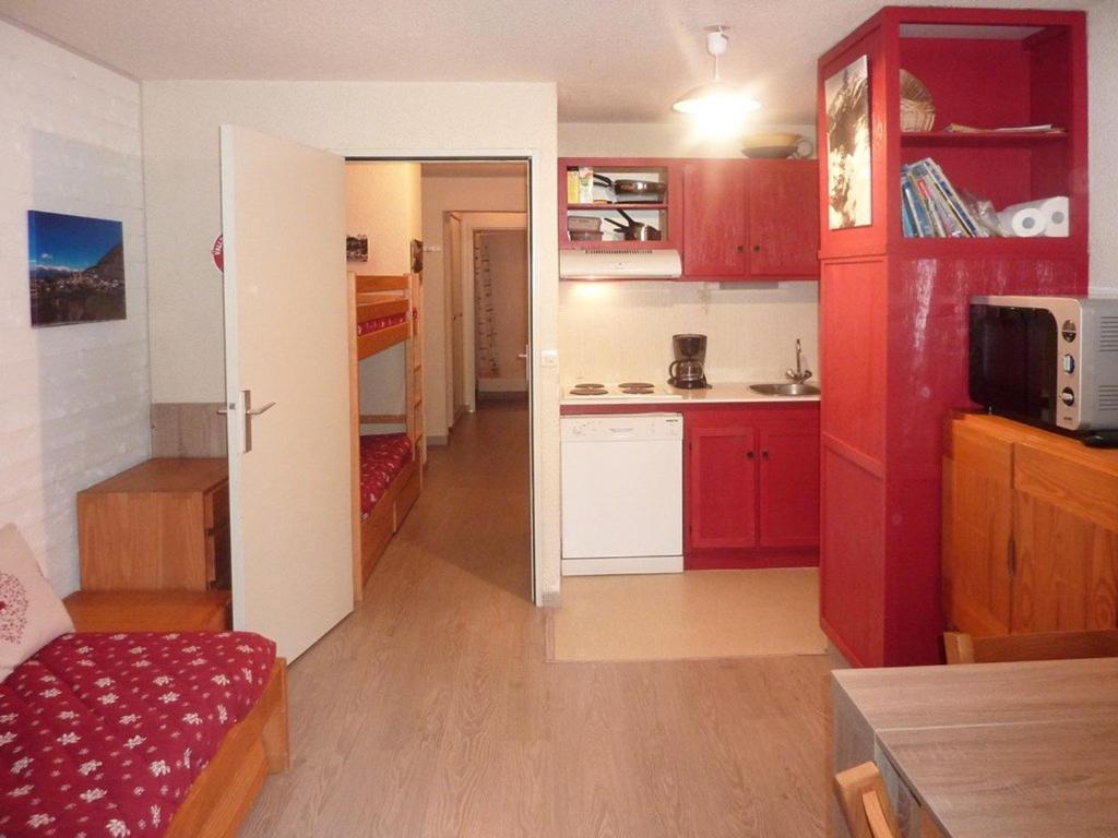 a room with a kitchen with red cabinets and a room with a table at Appartement Les Orres, 2 pièces, 6 personnes - FR-1-322-340 in Les Orres